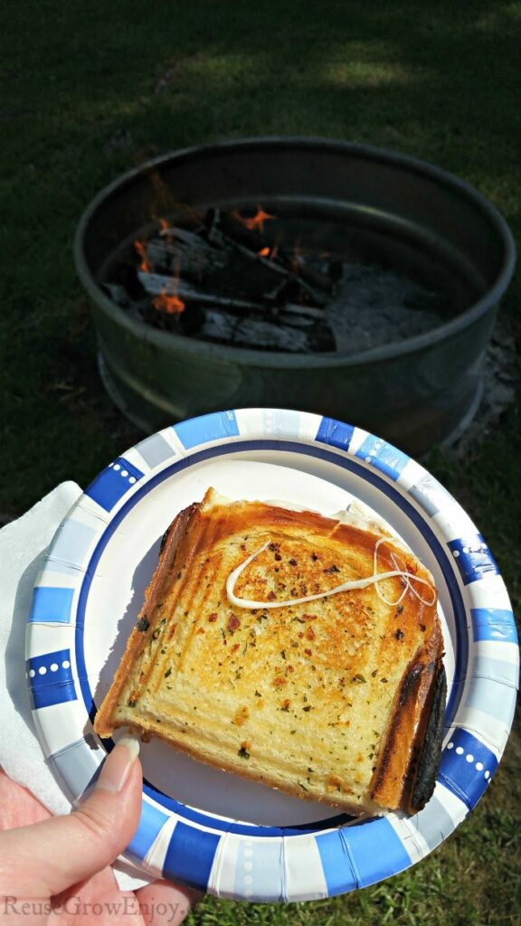 Grilled-Cheese-on-plate-with-campfire-in-background.